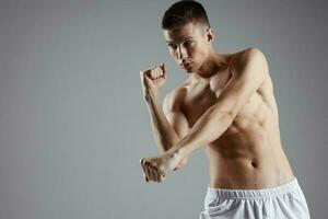 boxer with pumped up arm muscles on a gray background and abs cubes on his stomach photo