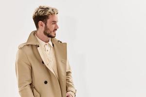 man with fashionable hairstyle in beige coat side view Copy Space isolated background photo