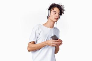 pelo rizado chico en auriculares con un teléfono en su manos música tecnología foto