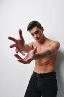 sexy man with a naked torso gesturing with his hands on a light background close-up model photo