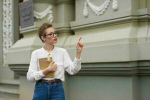 student with glasses walking around the city with a book education photo