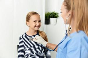 médico con estetoscopio cheque arriba un niño hospital salud foto