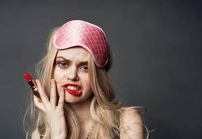 borracho mujer con lápiz labial en mano y rosado máscara en su cara foto