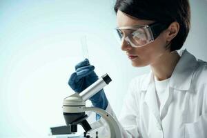 woman scientist in a white coat looking through a microscope study photo