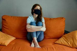 woman in black medical masks lockdown at home on the couch stay home concept photo