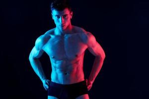 sexy man athlete in shorts holds hands on his belt on a black background photo