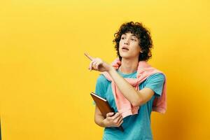 curly guy education with notepad hand gesture yellow background photo