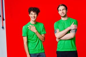 two men in green t-shirts are standing next to friendship red background photo