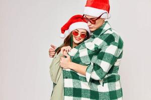 A man and a woman are hugging together in Christmas hats, sunglasses, holiday together photo