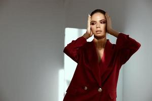 extravagant lady with bright makeup on her face touches her head with her hands on a dark background indoors photo