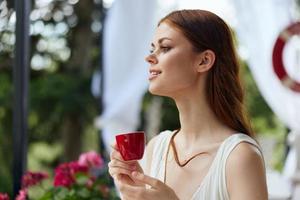 alegre mujer con rojo taza de café al aire libre café contento hembra relajante foto