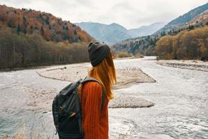 beautiful traveler with a backpack near the river in the mountains on nature landscape photo