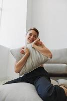 Teenage girl smile everyone sits at home near the couch and tosses up pillows, fun game and happiness without filters, copy place photo