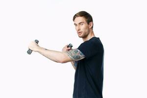 athlete in a black t-shirt are engaged in fitness on a white background indoors and dumbbells in hand photo