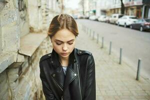 A woman in a leather jacket and glasses walks down the street in the city photo