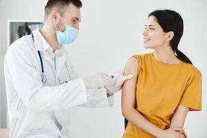 caring doctor in protective gloves to stick the injection to a woman covid vaccination photo