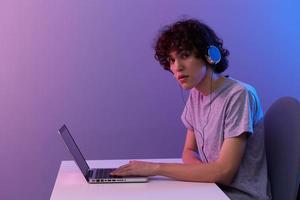 curly guy cyberspace playing with headphones in front of a laptop violet background photo