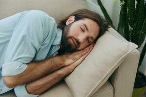 un hombre dormido en el sofá durante el día es cansado y relajado después estrés y sensación malo. estrés a trabajar, pobre dormir y salud problemas foto