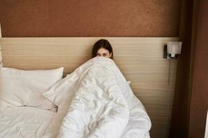 woman woke up early in the morning under the covers in bed photo