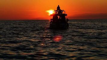 il barca e persone silhouette nel mare nel tramonto video