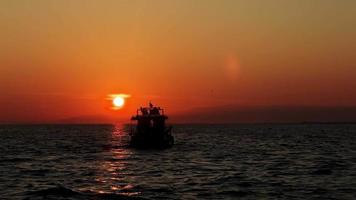 de boot en mensen silhouet in zee in zonsondergang video