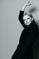 Fashion model girl posing with her hands up in the studio in black and white style in a classic jacket photo