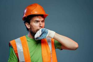 Bearded man in orange hard hat gloves professional cropped view blue background photo