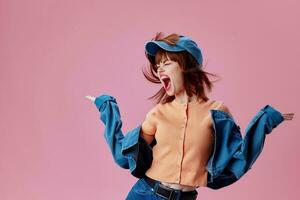 Pretty young female in a cap and denim jacket posing pink background unaltered photo