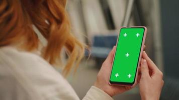 Over the sholder shot of woman watching green screen phone on the underground. video