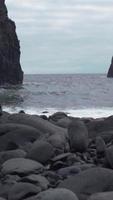 Large rock formations in the sea as waves crash on a stony shore video