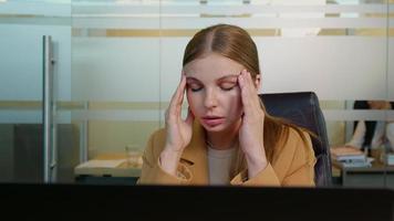 Office worker suffering from migraine in office, massaging temples. video
