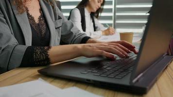 vicino su donna d'affari mani digitando su il computer portatile Lavorando in linea nel ufficio. video