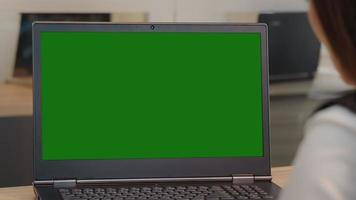 dichtbij omhoog groen scherm laptop en vrouw op zoek Bij scherm nemen aantekeningen in een notebook. video