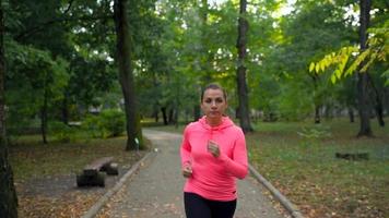 cerca arriba de mujer corriendo mediante un otoño parque a puesta de sol video