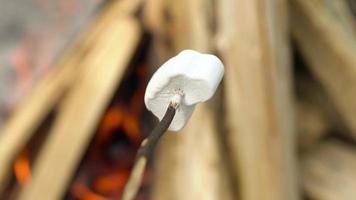 marshmallow är fräsning, rostning på de pinnar ovan de bål, utomhus video