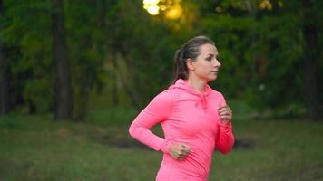 dichtbij omhoog van vrouw rennen door een herfst park Bij zonsondergang video