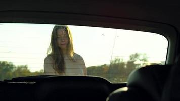 mujer pone compras pantalones en un coche asiento y se sienta en él, pretendiendo a conducir lejos. video