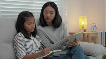 Mutter Lehren Lektion zum Tochter. asiatisch jung wenig Mädchen lernen beim heim. tun Hausaufgaben mit nett Mutter Hilfe, ermutigen zum Prüfung.. Mädchen glücklich Schule zu Hause. Mama Rat Bildung zusammen. video