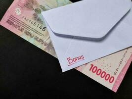 un blanco sobre escrito de prima y nuevo indonesio billetes de banco, por lo general tunjangan hari raya o llamado thr son dado a empleados adelante de Eid. foto