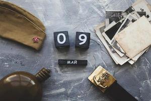 Flask, cap, soldier belt with a five-pointed star with a hammer and sickle. old photographs of the war years and a wooden calendar with the date May 09.  Victory Day .Russian text on May 9 photo