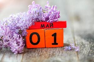 de madera calendario con ruso texto mayo 1 y un ramo de flores de lilas en un de madera fondo.primavera día, vacío espacio para texto. internacional de los trabajadores día foto