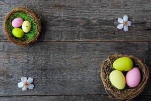 Easter quail painted eggs  in a nest and spring flowers on a  wooden background.   An Easter card with a copy of the place for the text.Top view. photo