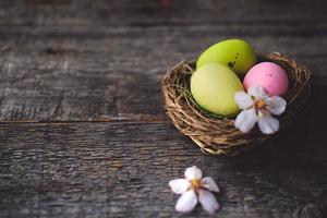 Easter quail painted eggs  in a nest and spring flowers on a  wooden background.   An Easter card with a copy of the place for the text.Top view. photo