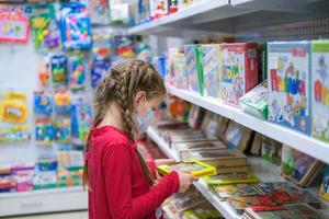 Krasnodar, Russia March 7, 2021. A child in a medical mask is choosing a children's toy in the store. A girl is shopping amid the COVID-19 pandemic. photo