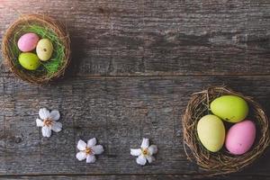 Easterquail colored eggs  in a nest on a  wooden background.   An Easter card with a copy of the place for the text.Top view. photo