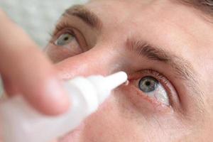 Man drops eye drops install lenses. photo