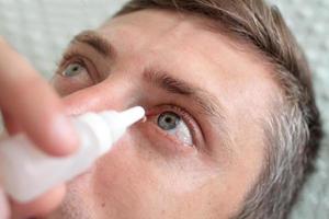 Man drops eye drops install lenses. photo