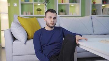 Portrait of a thoughtful, unhappy and depressed man at home. Man sitting on the ground with his back depressed and sad. video