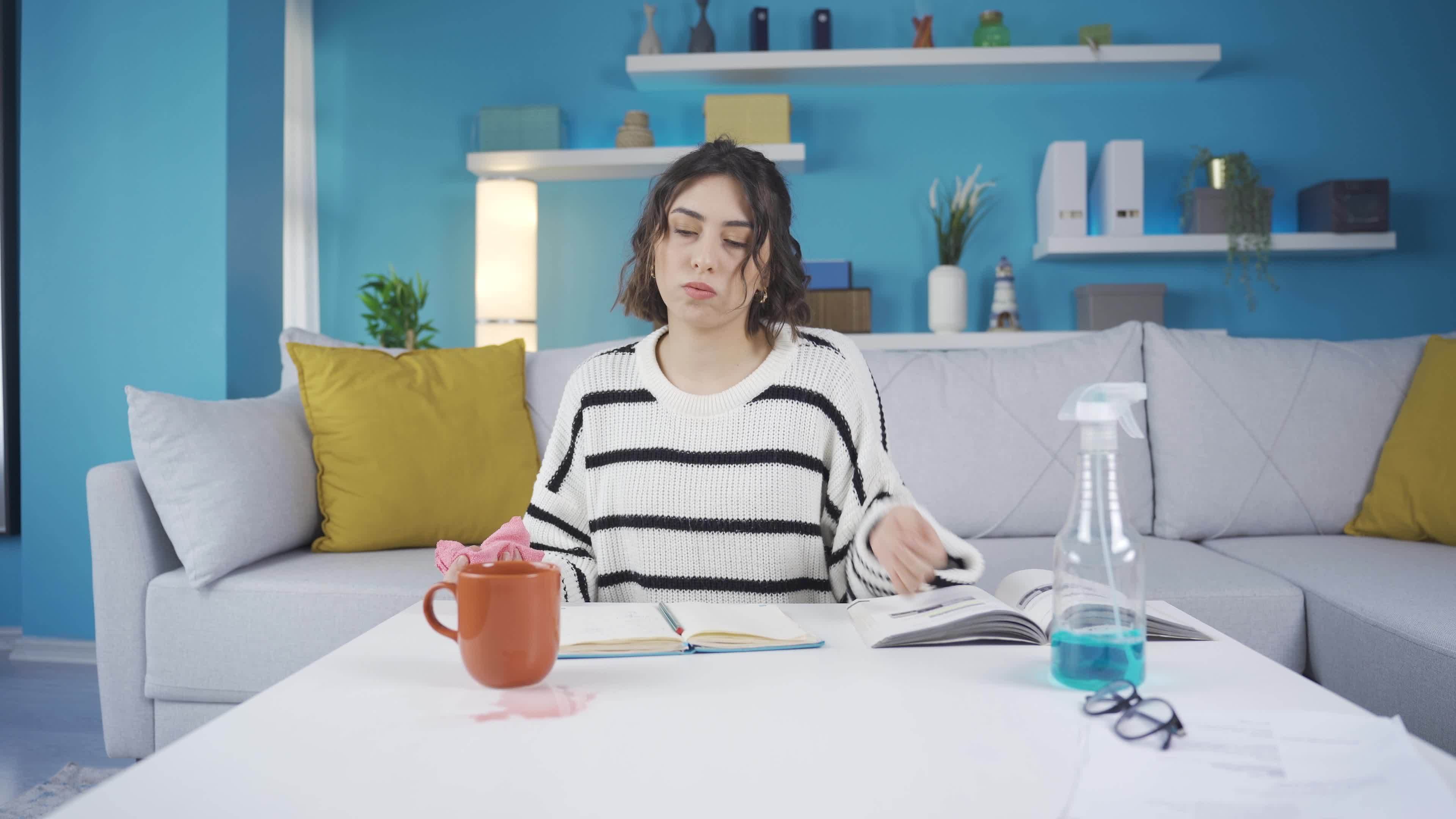 Woman cleans spilled liquid stain on her desk. Woman cleaning spilled