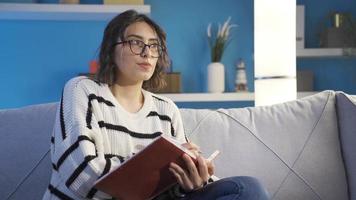 le femme qui écrit sa souvenirs dans une agenda. réfléchi et émotif femme l'écriture agenda. elle câlins sa journal intime et soupirs. video